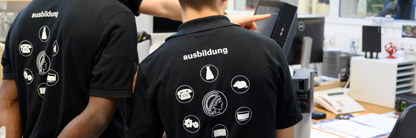 Image showing the backs of two persons wearing T-Shirts with different symbols for the vocational trainings at the institutes